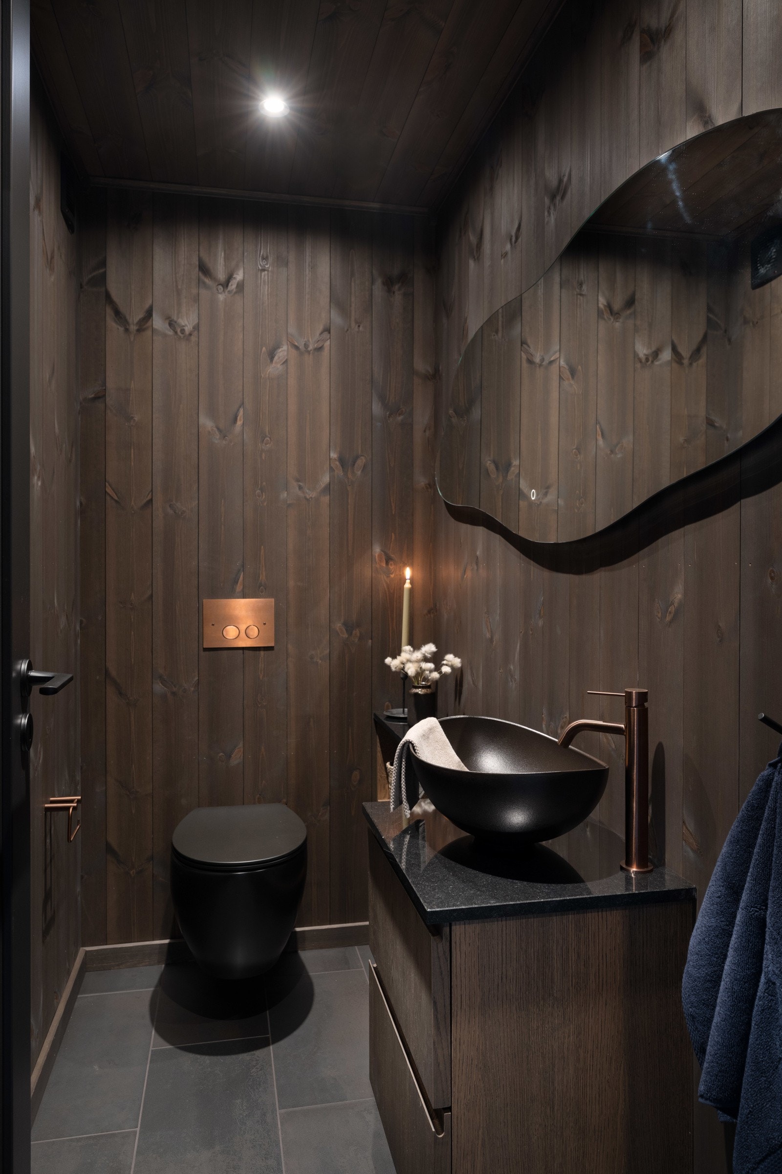Det er ekstra toalett i samme stil som resten av hytten med organisk speil, kobberdetaljer og stein benkeplate