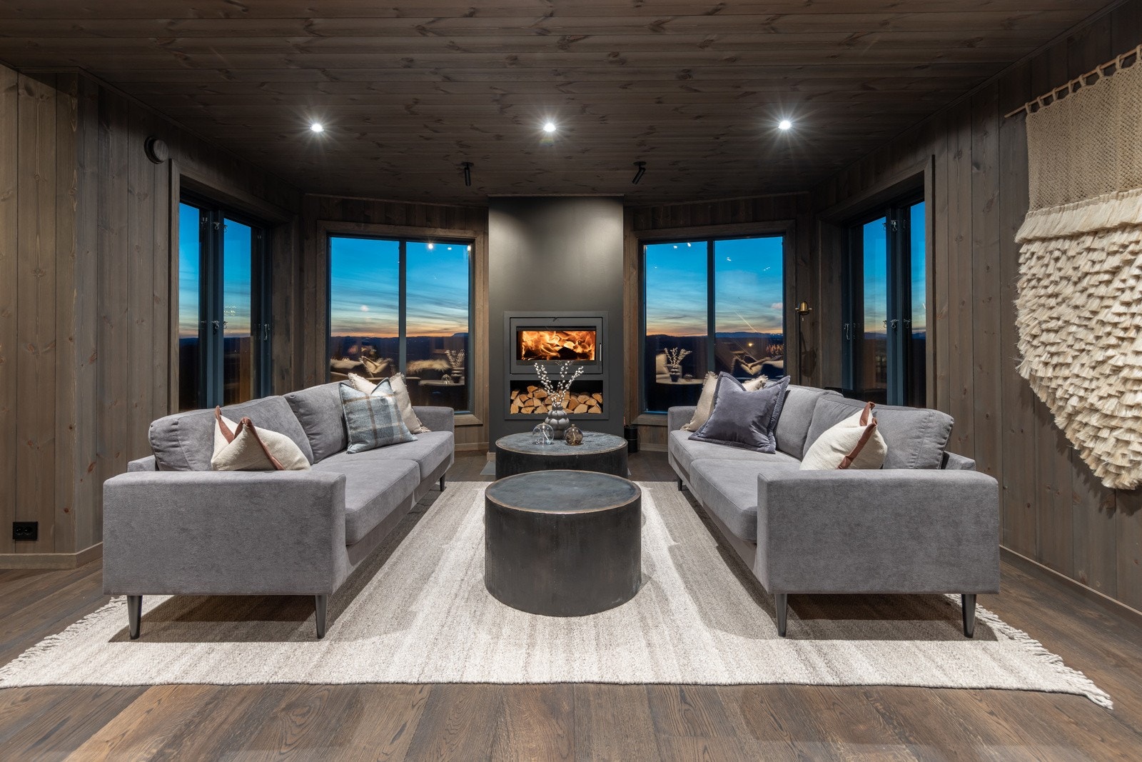 Velkommen inn! En av hyttas to stuer med store vinduer, peisinnsats og ferdig møblert sofagruppe