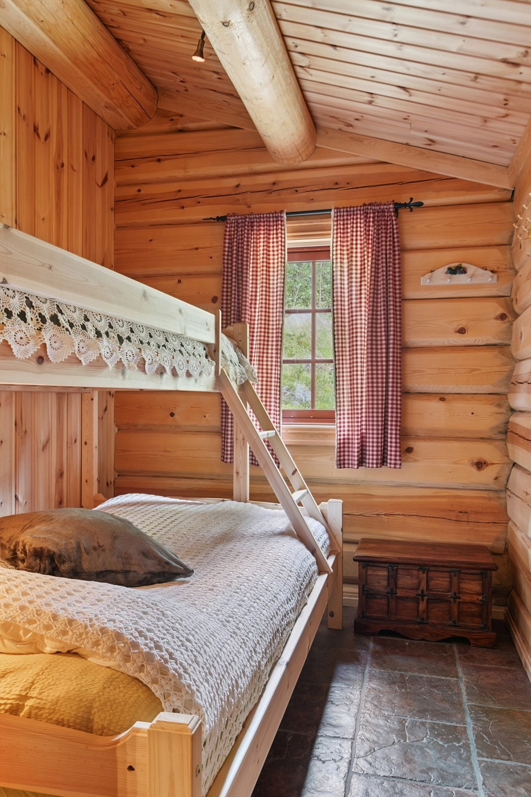Et av hyttas tre soverom, med sjarmerende laftevegger og familiekøyeseng. Galleribilde
