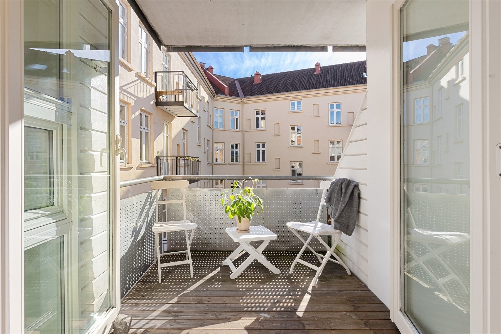 Utgang med dobbelfløyet dør til overbygget sydvendt balkong ut mot stille bakgård Galleribilde