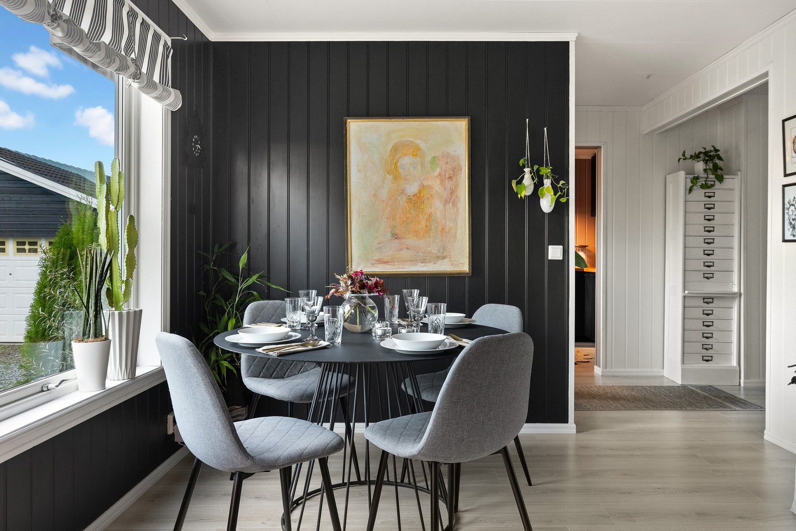 Stuen er åpen og innbydende med dempet sort på veggene og laminat på gulvene. Galleribilde