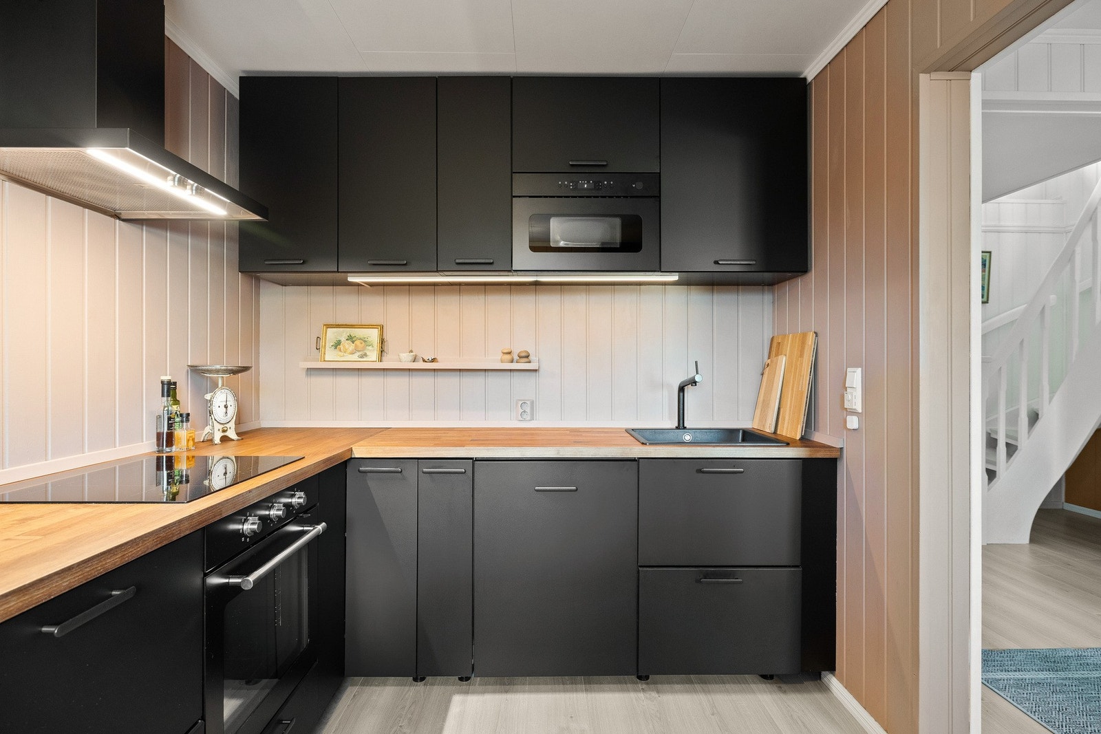 Kjøkkenet er renovert i 2024 og har innredning med sorte glatte fronter og en slitesterk benkeplate i lamimat. Galleribilde