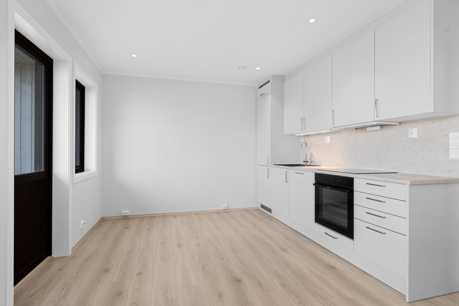 Takhøy kjøkkeninnredning fra Mesterkjøkken med lyse, slette kjøkkenfronter og med lys grå steinmønstret laminat benkeplate. Kjøkkenet leveres komplett med hvitevarer Galleribilde