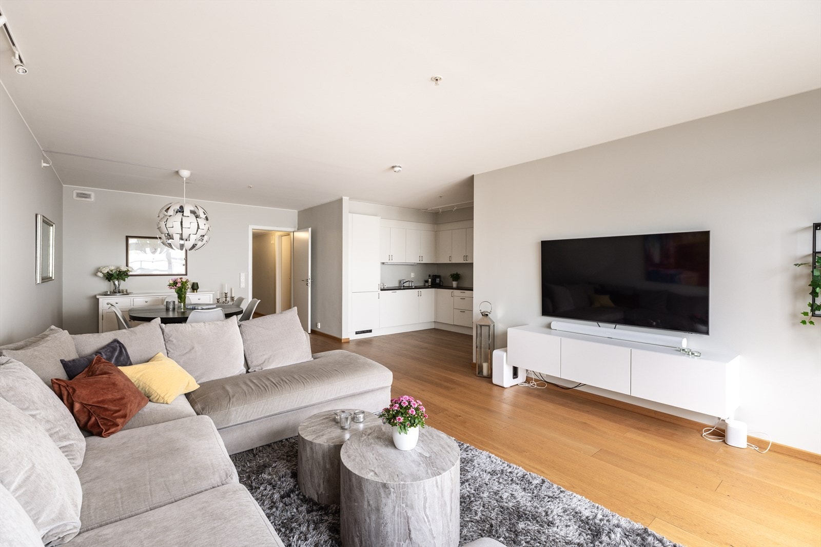 Romslig oppholdsrom med naturlig inndeling for både TV-stue og spiseplass, samt kjøkken i åpen løsning Galleribilde