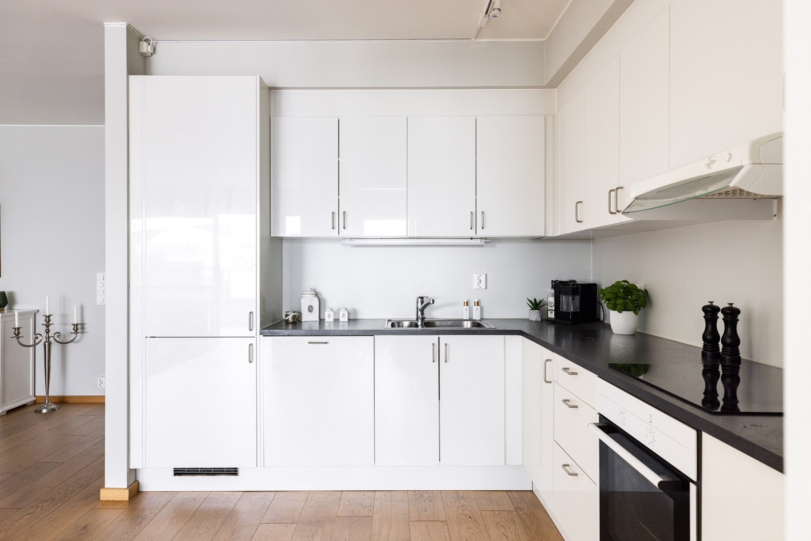 Stilrent kjøkken innredet med glatte fronter med integrert kjøl/fryseskap, stekovn, platetopp og oppvaskmaskin. Mekanisk avtrekksvifte over stekesonen Galleribilde