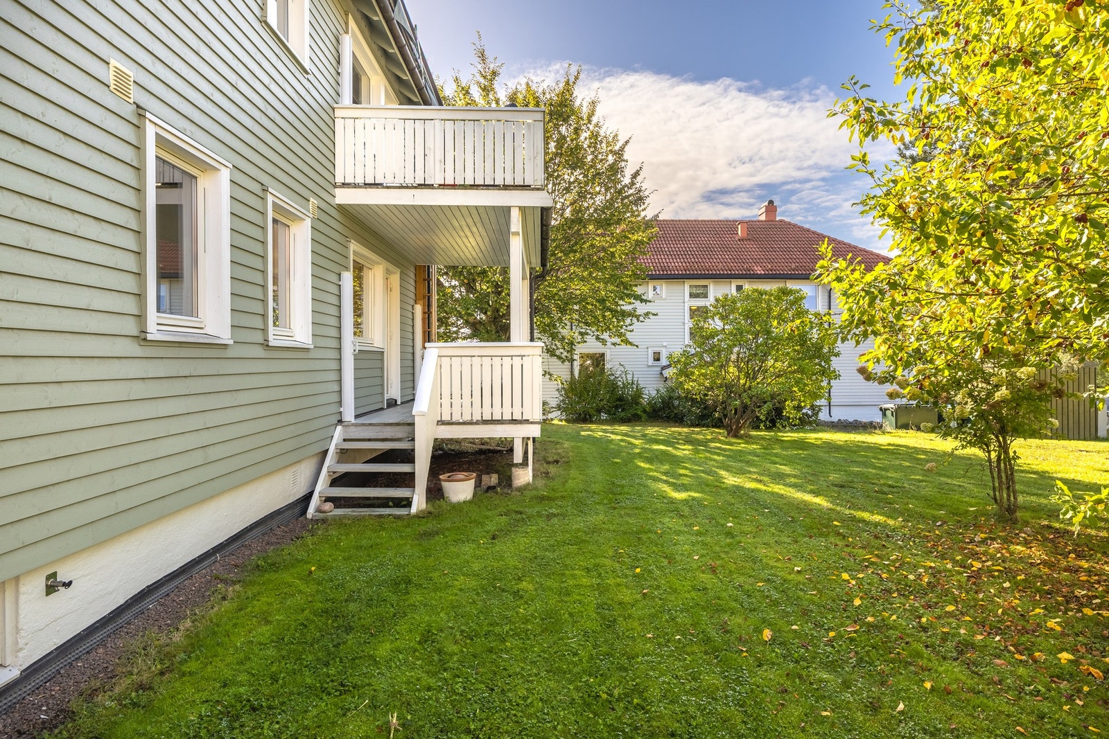 Balkongen har to uttrekkbare skjermvegger, og det er trapp ned til en stor gressplen på fellesarealet. Galleribilde