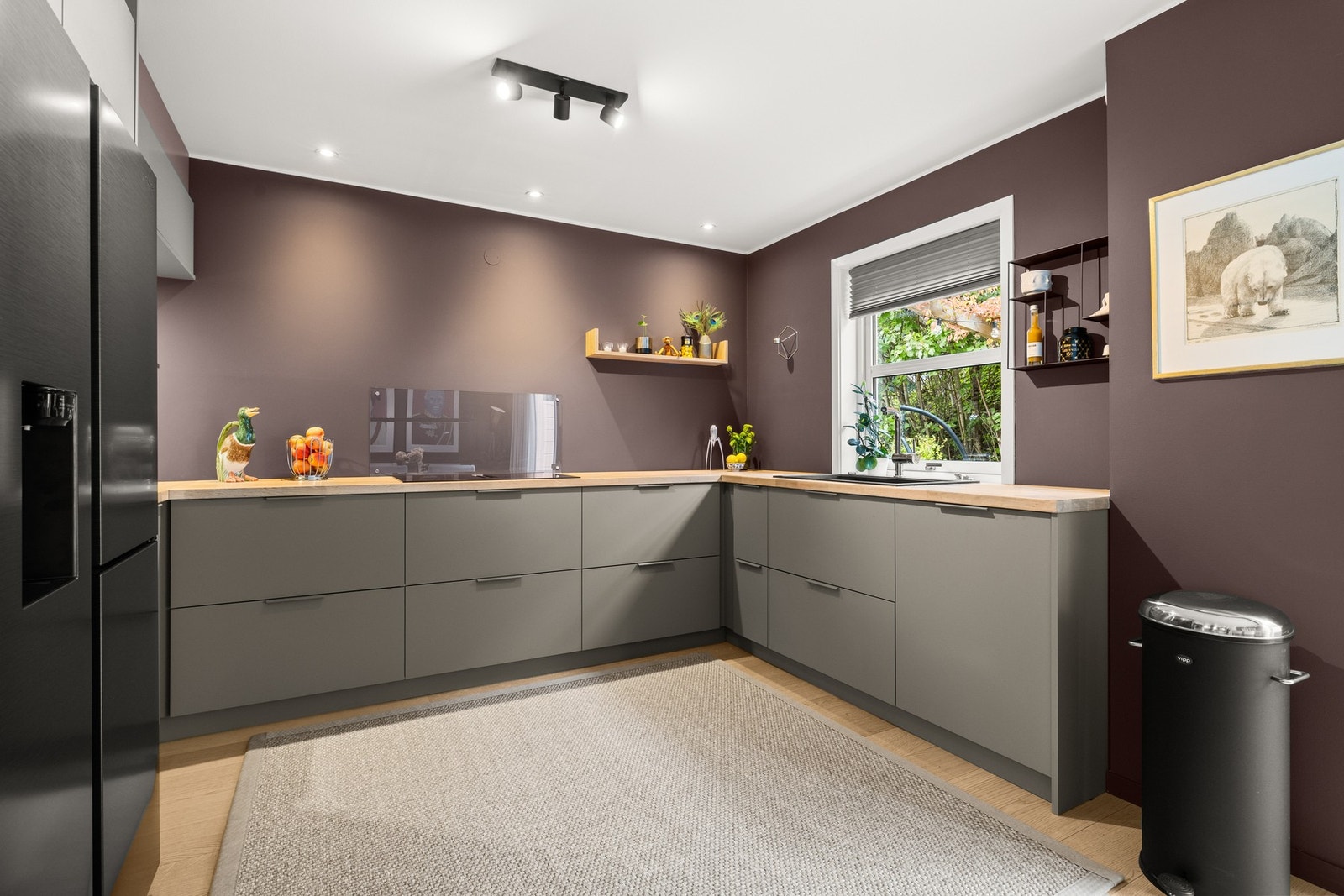Kvik kjøkkeninnredning fra 2025 med glatte fronter i fargen clay (leire) og benkeplater i heltre eik. Downlights i himlingen og i nisje under overskap. Galleribilde