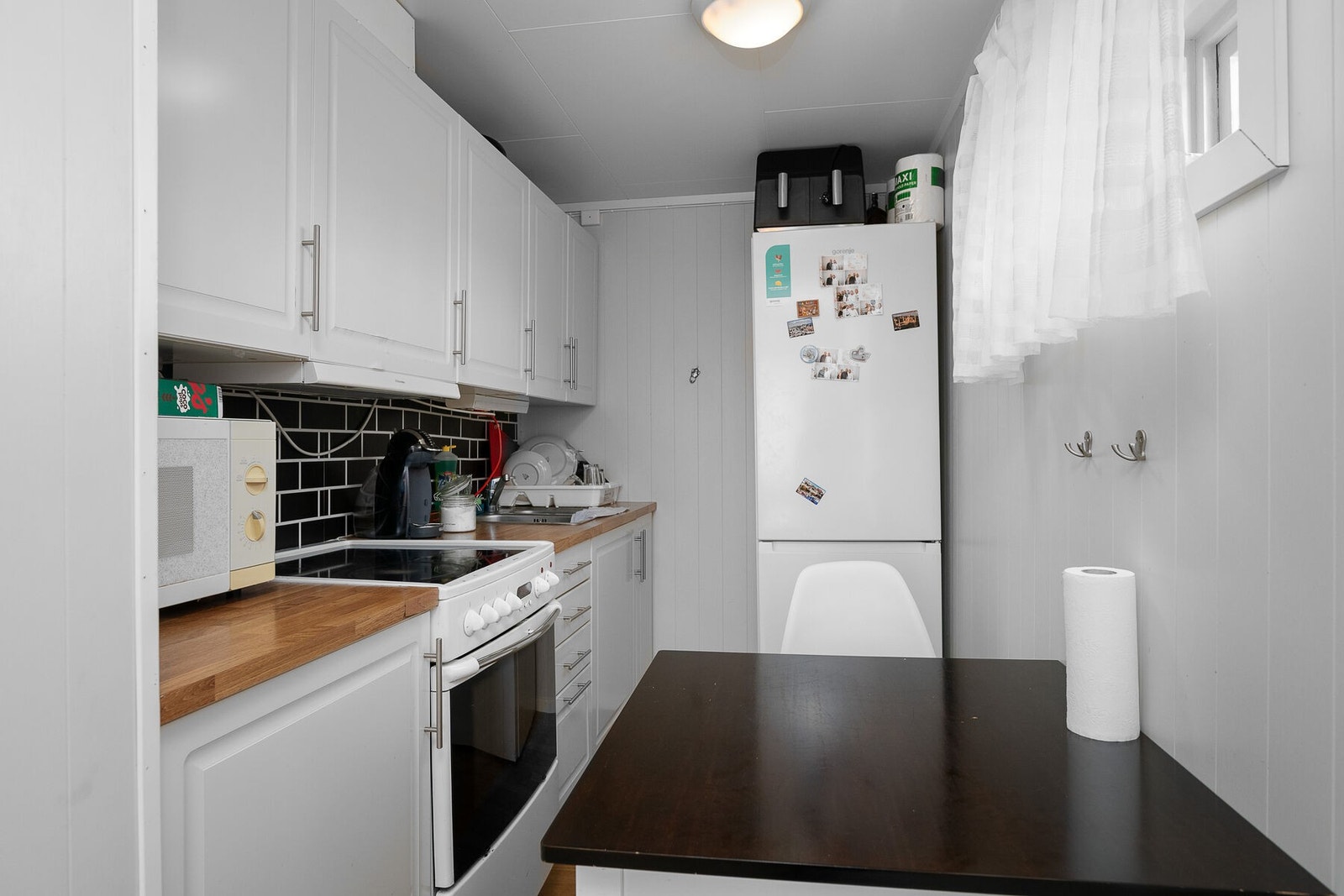 Kjøkken med opplegg for frittstående hvitevarer, og plass til spisebord. Galleribilde