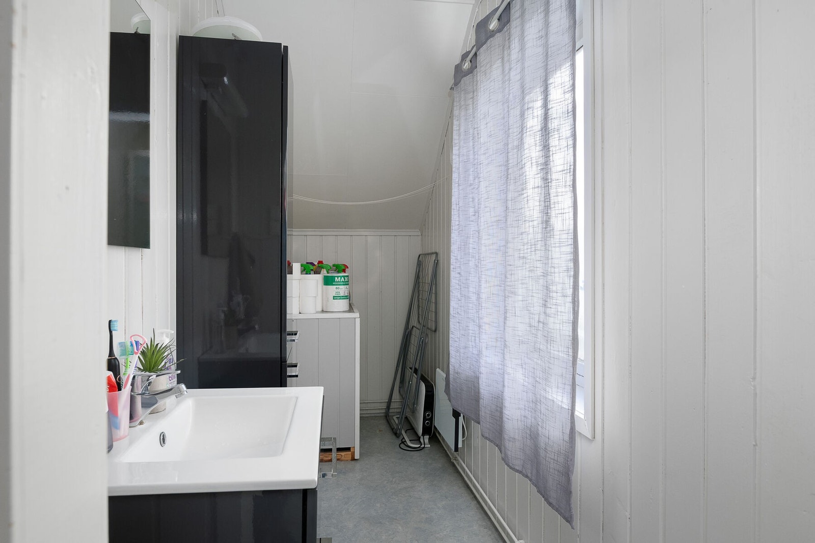 Baderom med servant på skuffeseksjon, høyskap, toalett og dusjkabinett. Galleribilde