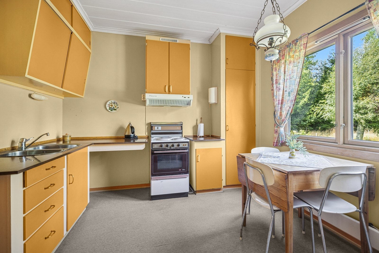 Eldre malt kjøkkeninnredning med foliert benkeplate. Oppvaskkum. Det er kjøkkenventilator med avtrekk ut. Galleribilde