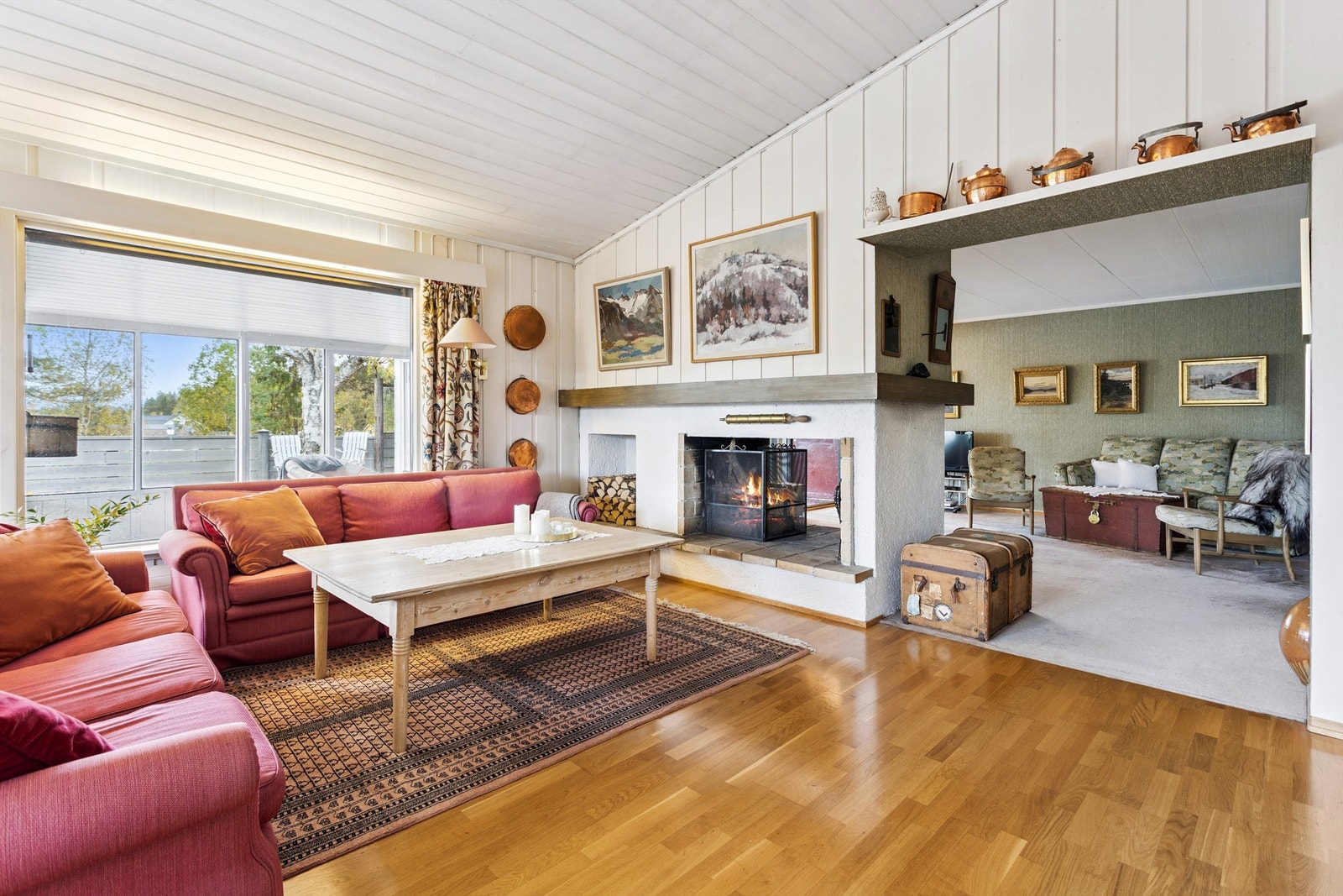 Hovedstuen er romslig og har en flott gjennomgående peis. Legg merke til skråhimlingen som gir en luftig atmosfære. Galleribilde