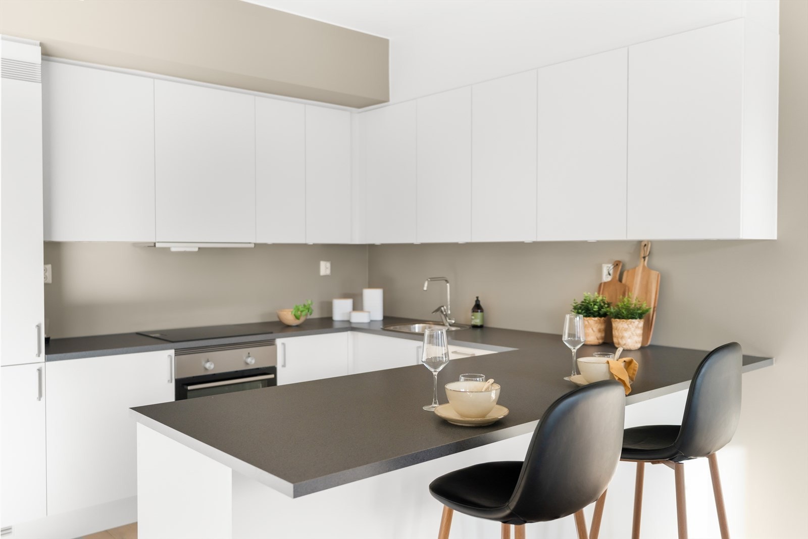 Det er hvite, glatte fronter, grå benkeplate og integrerte hvitevarer. Galleribilde