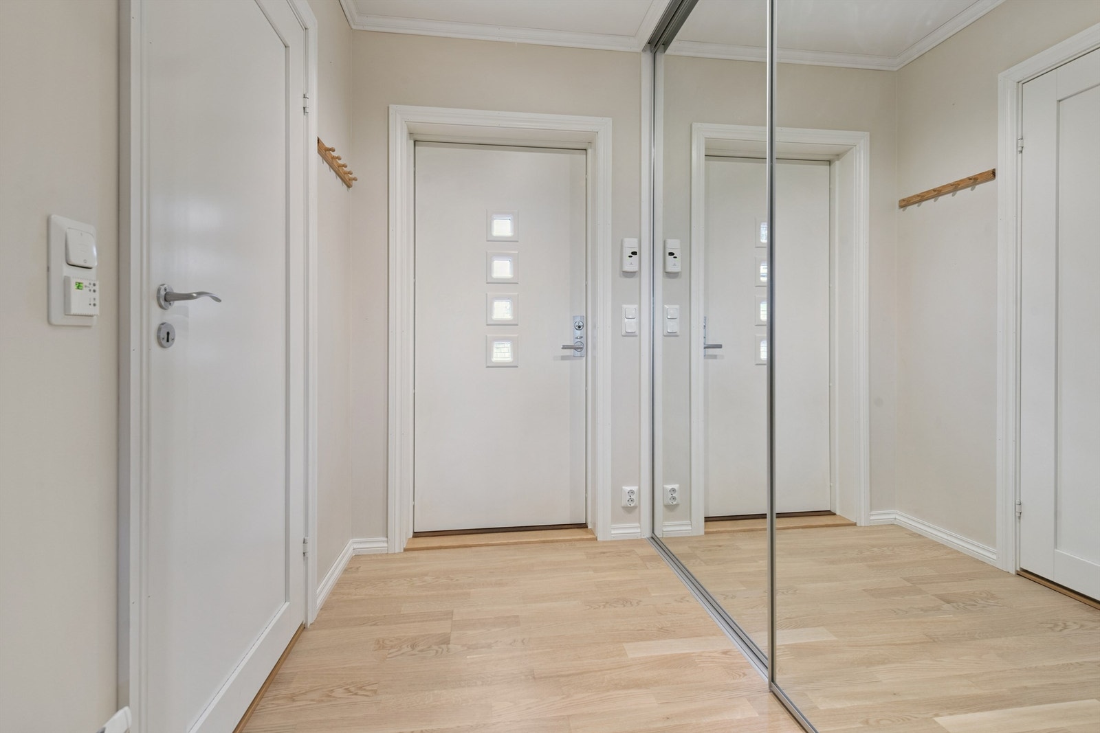 Du ønskes velkommen inn i en lys entré med parkett på gulvet og god oppbevaringsplass i en romslig skyvedørsgarderobe med speilfronter. Galleribilde