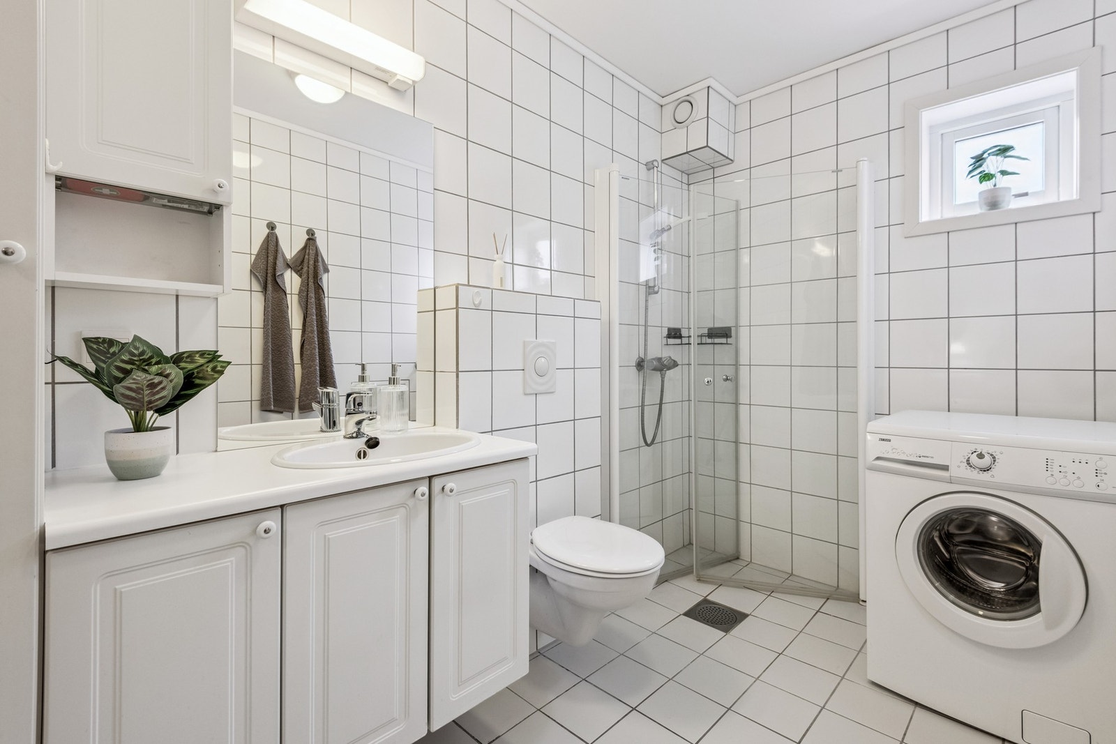 Flislagt bad med gulvvarme, dusj, vegghengt toalett og servant. Galleribilde