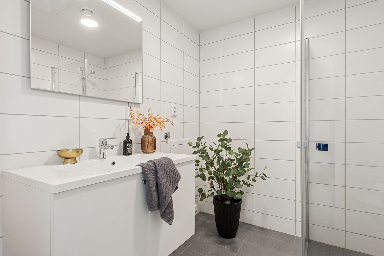 Badet har servant med underskap, speil, dusjhjørne, toalett og opplegg for vaskemaskin. Galleribilde