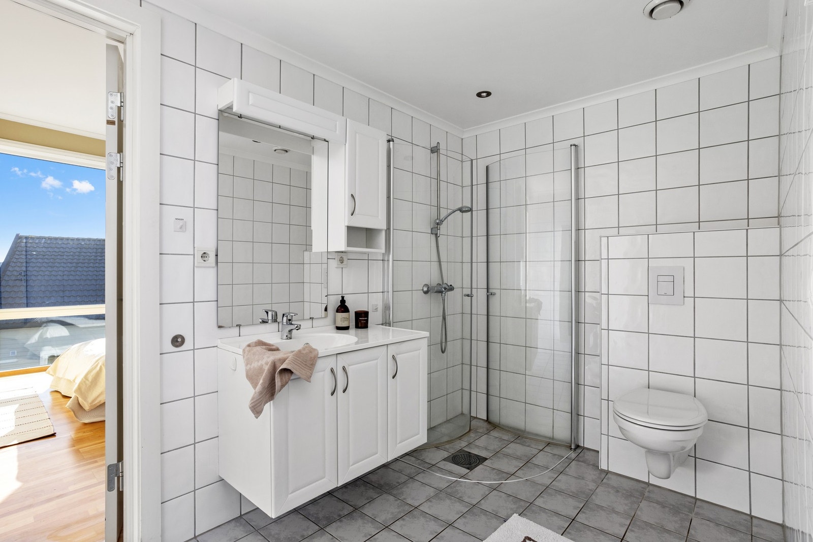 Flislagt bad med spotter, dusjhjørne, toalett og servant. Galleribilde