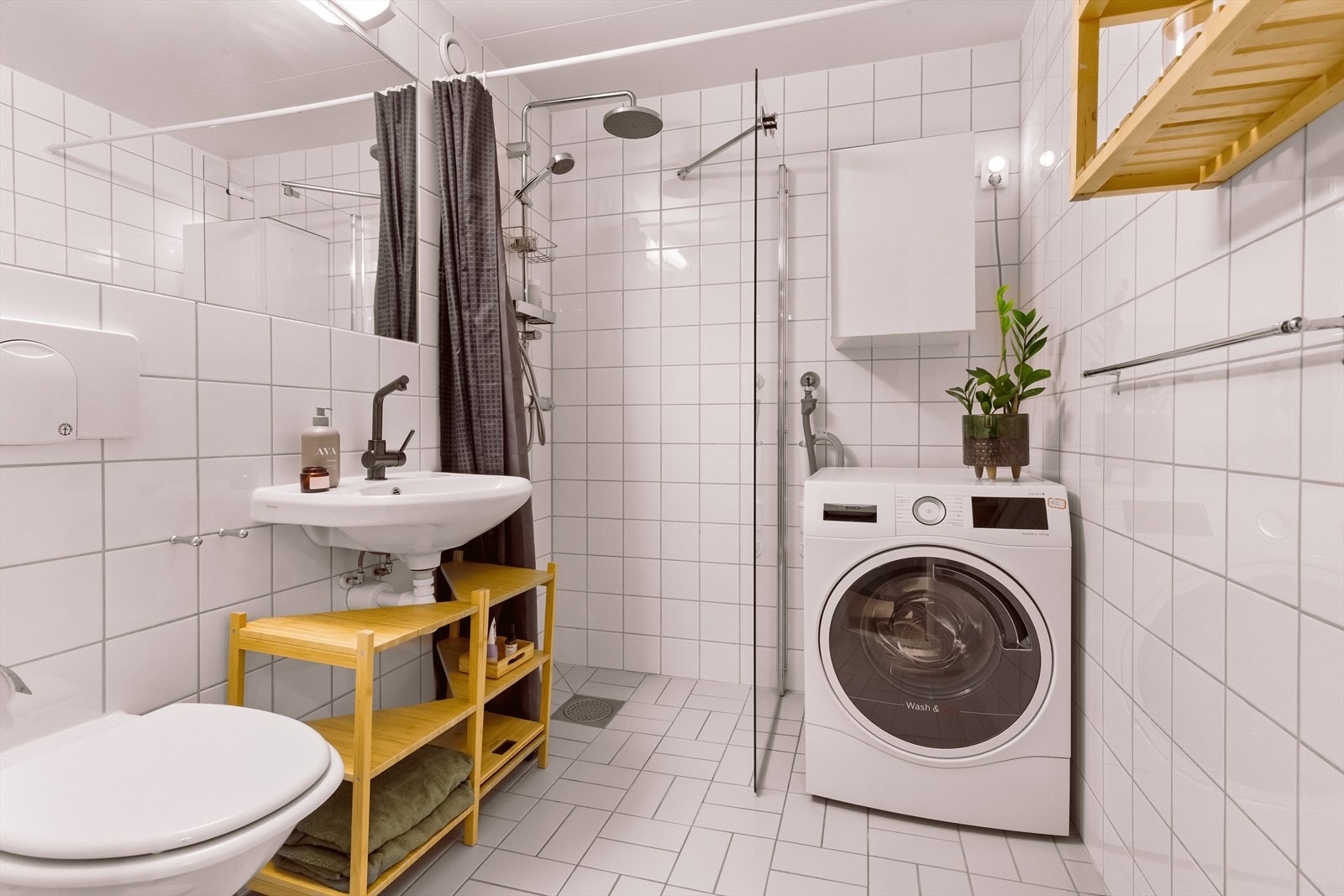 Badet er innredet med servant, stort speil, dusjnisje og veggmontert toalett. Galleribilde