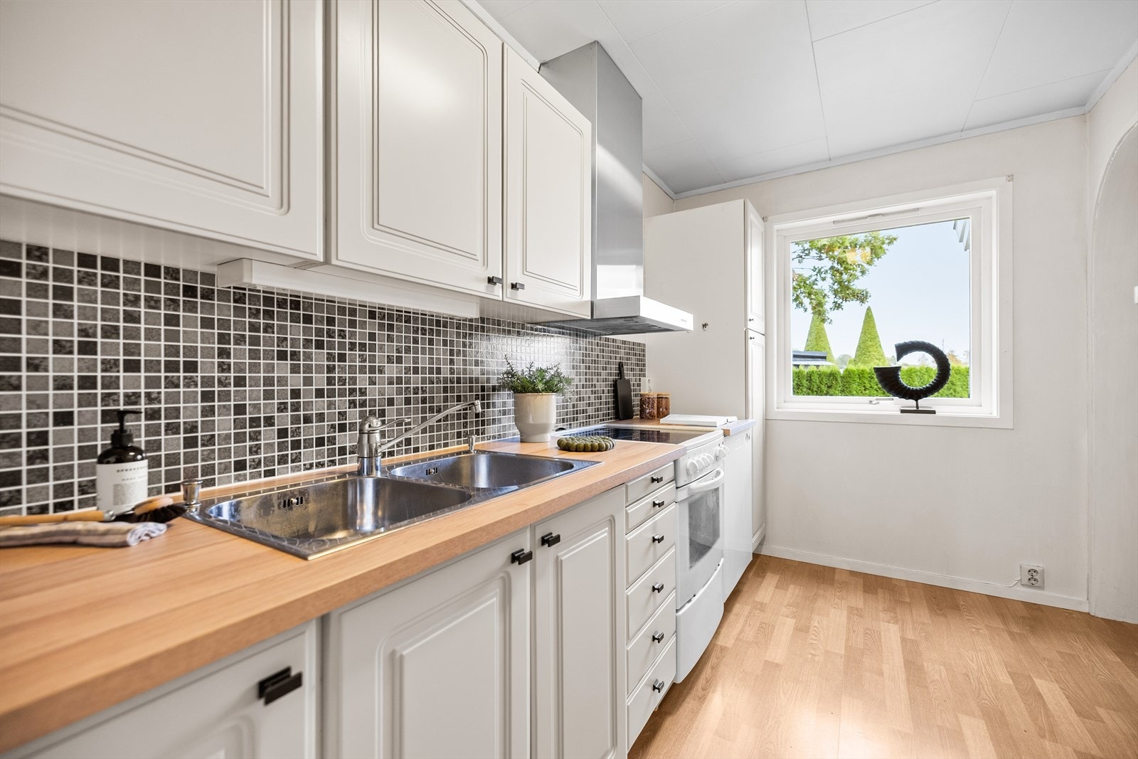 Innredningen består av profilerte fronter kombinert med en benkeplate i laminat, og det er lagt fliser mellom benk og overskap - en detalj som både er pent og lett å holde rent. Galleribilde