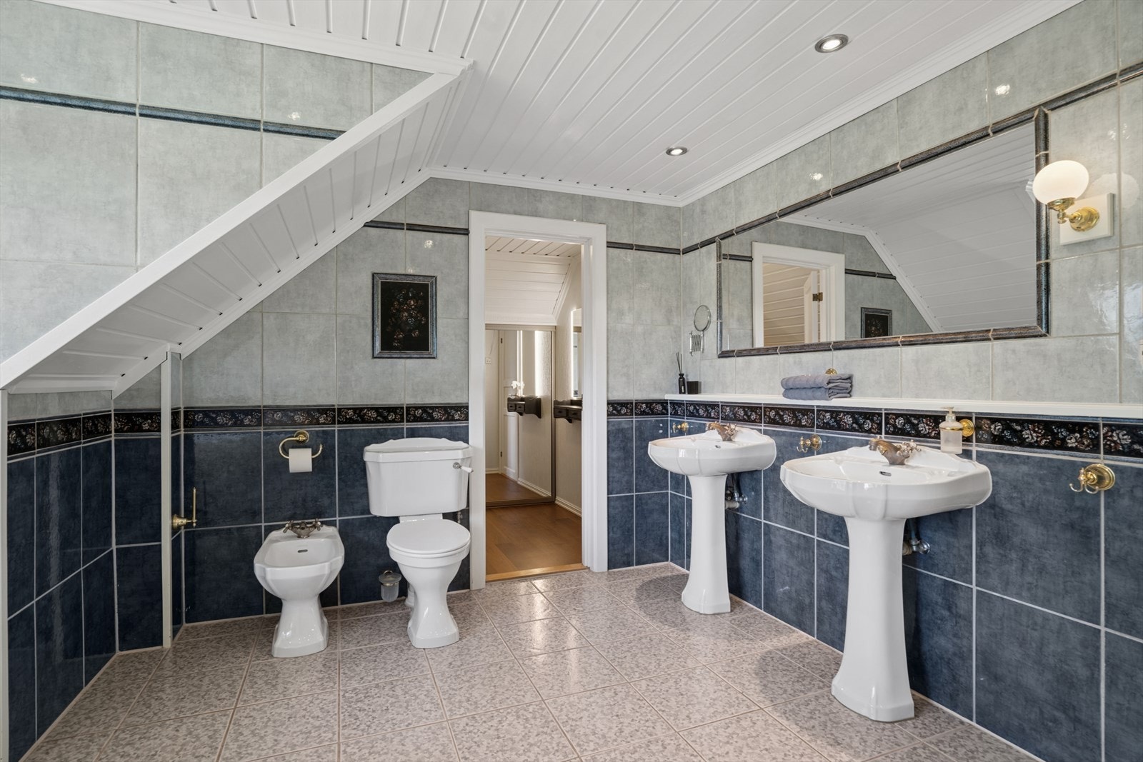 Badet er utstyrt med to servanter, gulvstående toalett, bidet, dusjkabinett og et hjørnebadekar. Galleribilde