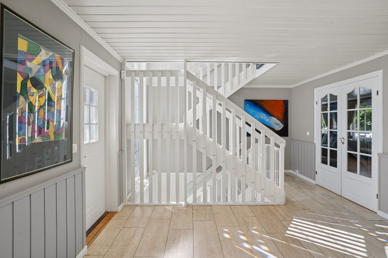 Man ønskes velkommen inn i en romslig hall med rikelig med lysinnslipp fra det store vinduet i trappeløpet. Videre er det fløydør mot den store stuen. Galleribilde