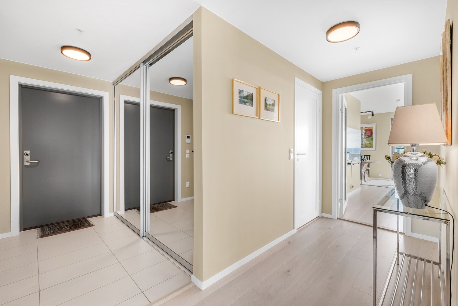 Vel innenfor døren til leiligheten blir du møtt av en romslig og lekker entré/gang med fliser og parkett på gulvet. Her er det installert en stor skyvedørsgarderobe og i tillegg finner man her en praktisk innvendig bod. Galleribilde
