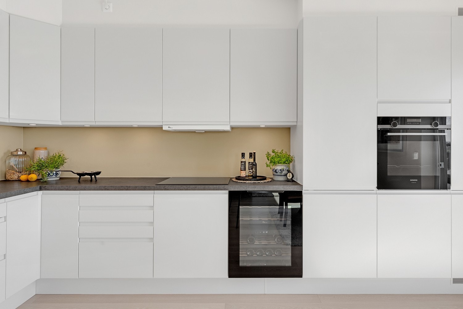 Leiligheten har et stilfullt HTH kjøkkeninnredning fra 2023 utført med hvite, glatte fronter og mørke laminerte benkeplater med nedfelt kjøkkenkum. Her er det godt med skap, skuffer og benkeplass samt integrerte hvitevarer. Galleribilde