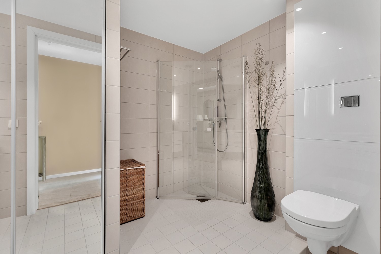 Hovedbadet er innredet med en pen baderomsinnredning med underskap og heldekkende servant, dusjhjørne, veggmontert toalett, og opplegg for vaskemaskin i nisje bak skyvedører. Galleribilde