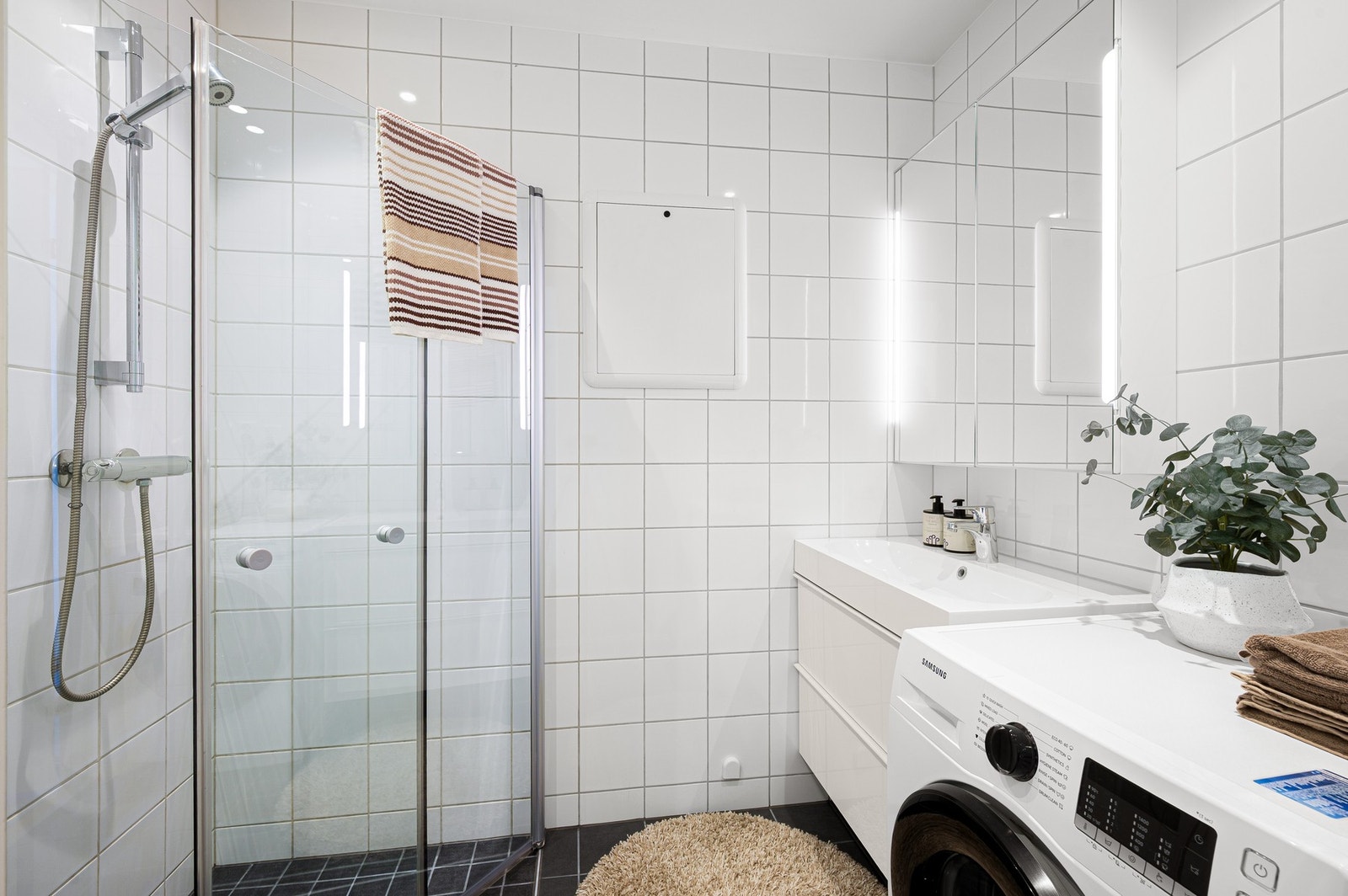 Pent baderom fra 2014 med dusjhjørne, servantinnredning og opplegg for vaskemaskin. Galleribilde