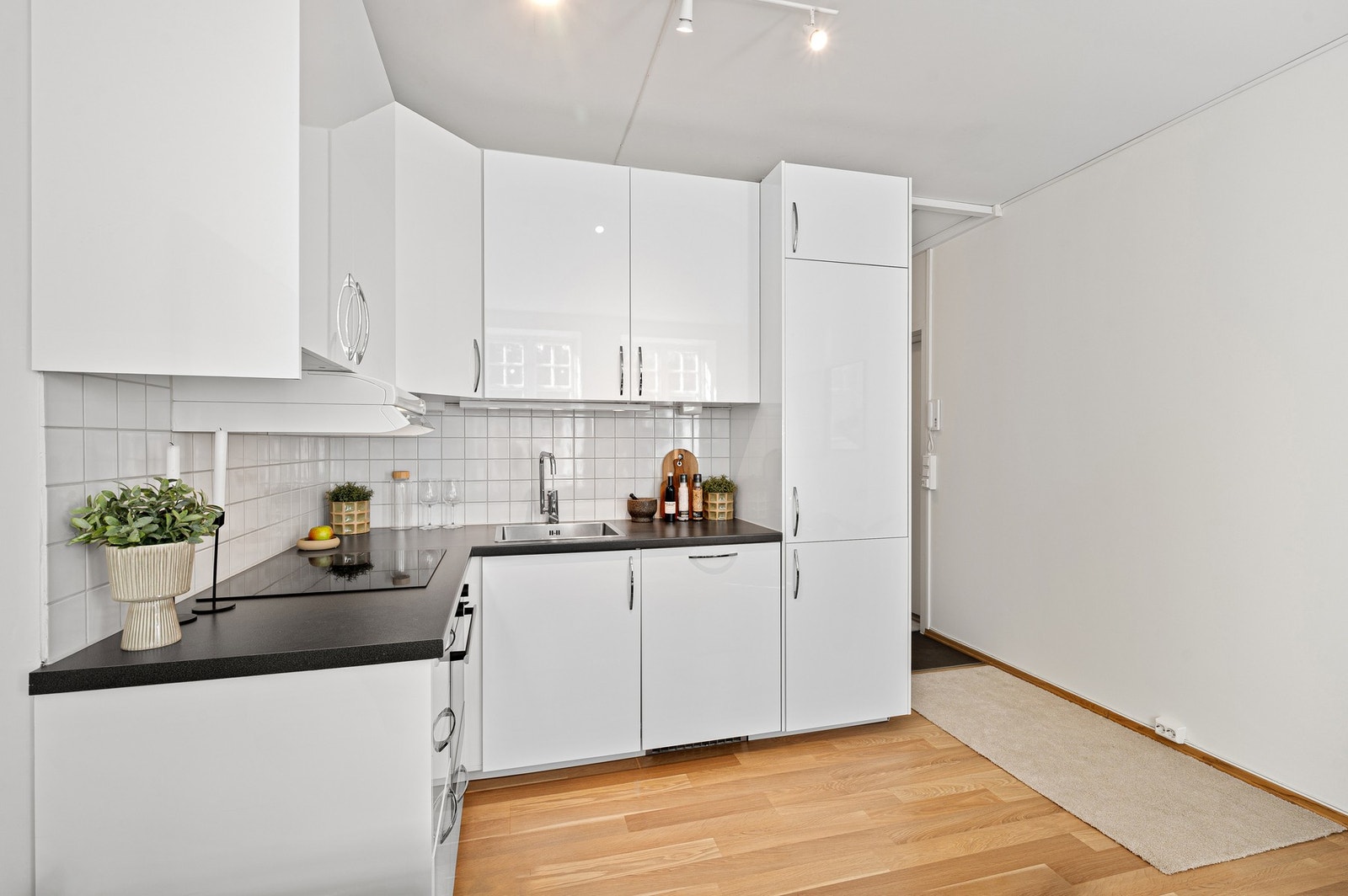 Pent kjøkken fra 2014 med hvite fronter og mørk benkeplate. Galleribilde