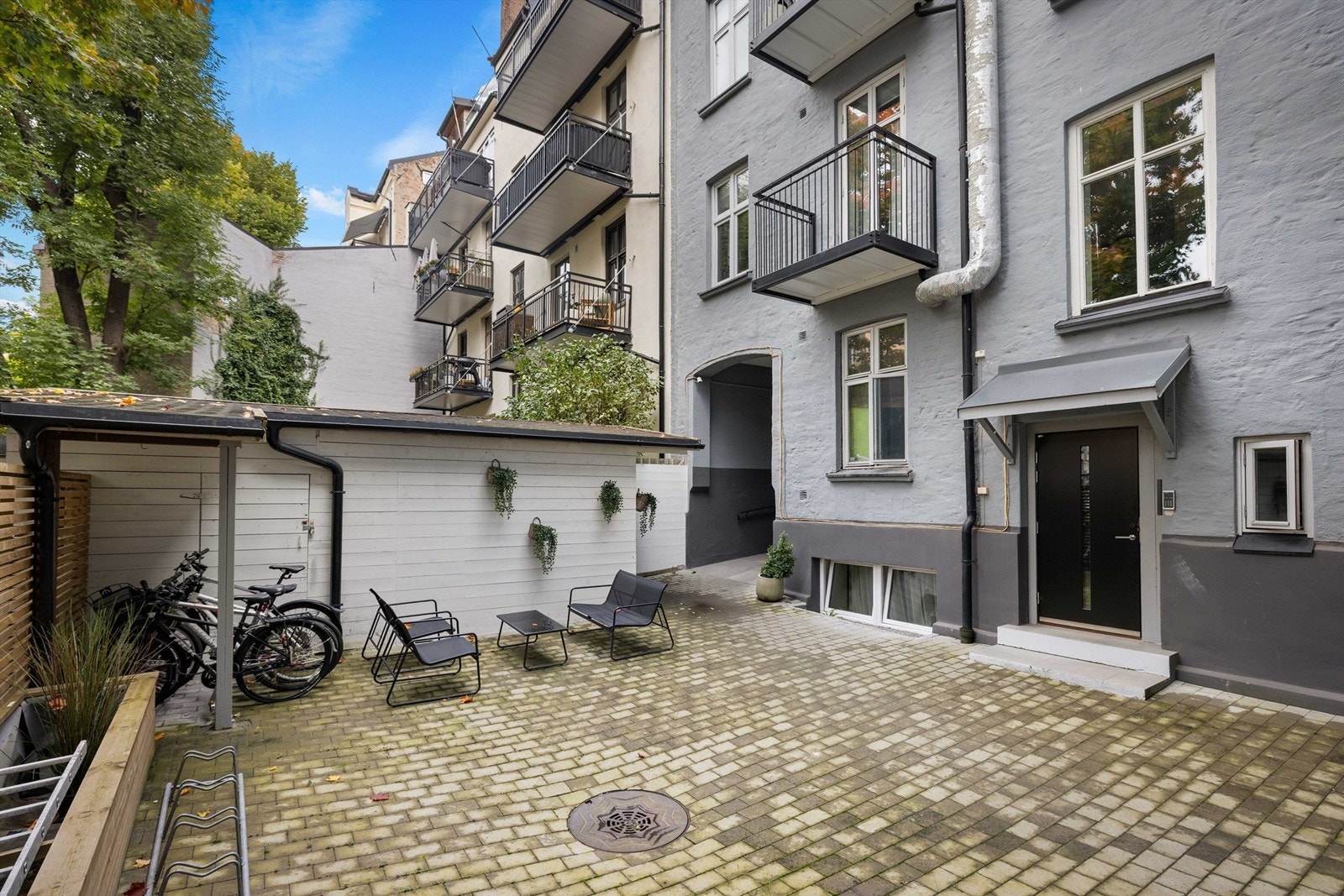 Bakgården er opparbeidet med asfalterte arealer, sittegruppe og sykkelparkering. Galleribilde