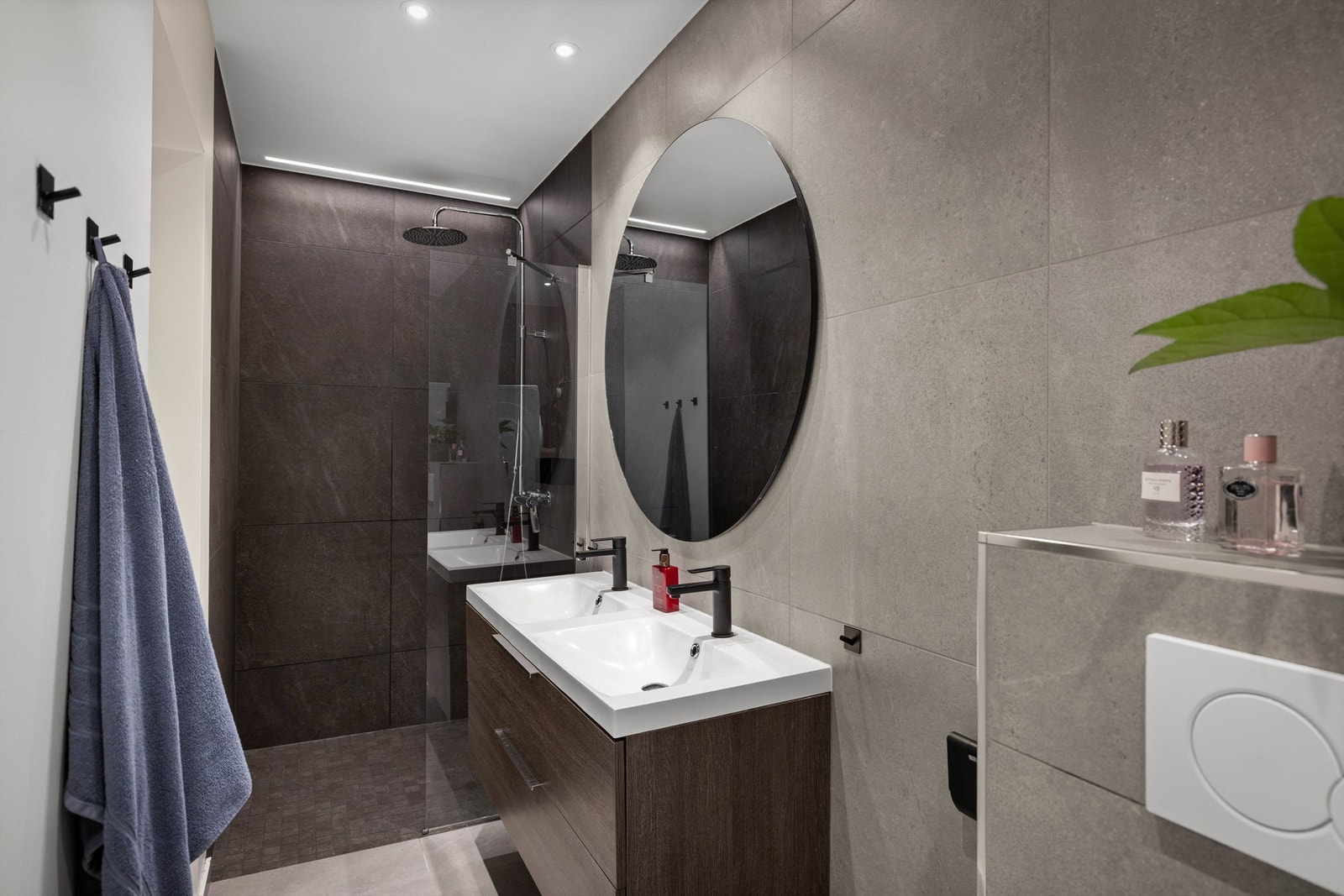 Moderne og tidsriktig baderom pusset opp i 2019. Badet inneholder veggmontert toalett, skap, varmtvannsbereder, regnfallsdusj med dusjvegg i glass og dobbel servantinnredning med skuffer under. Galleribilde
