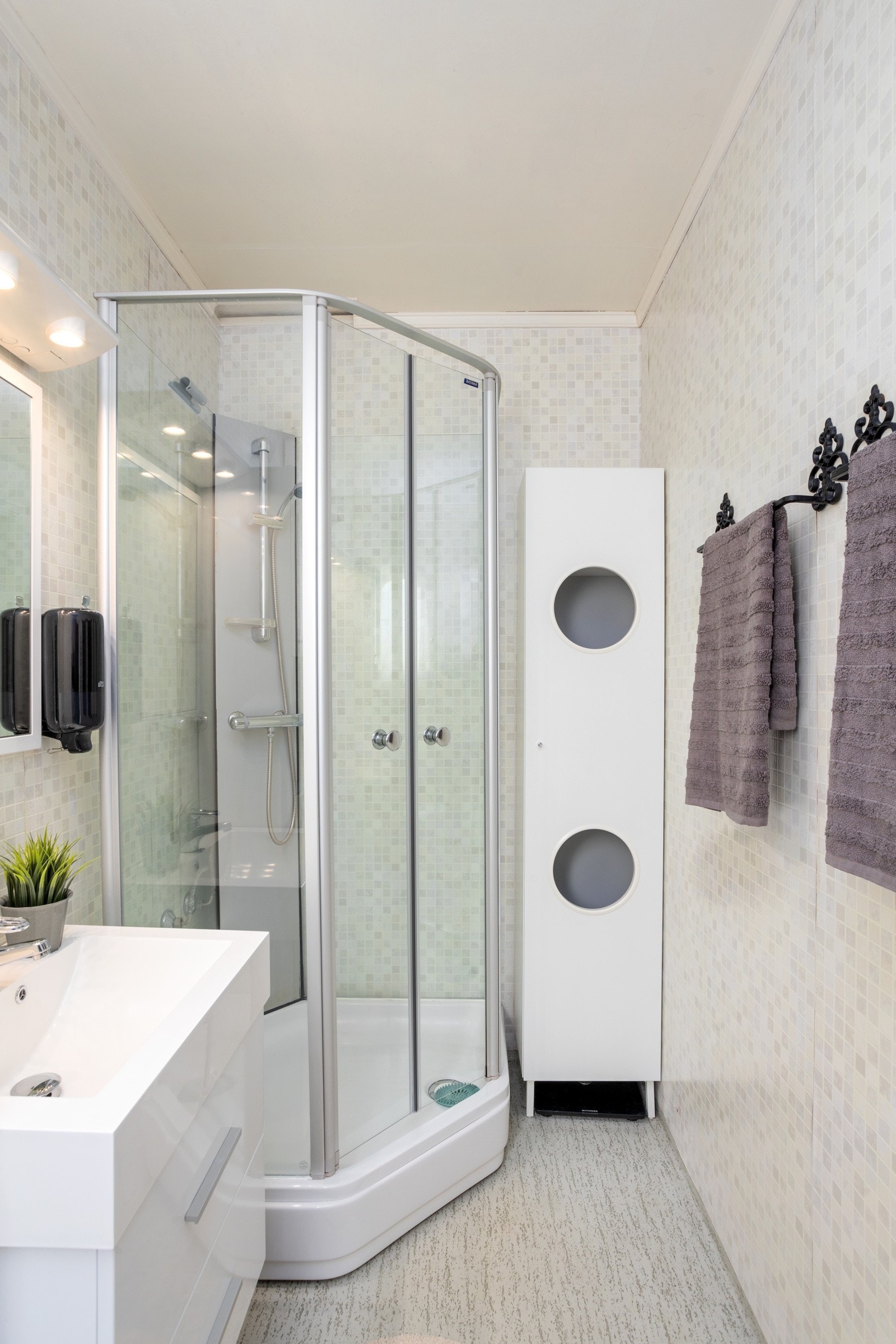 Baderommet inneholder servant, speil og overlys med stikkontakt på vegg over servant, dusjkabinett og wc. Galleribilde