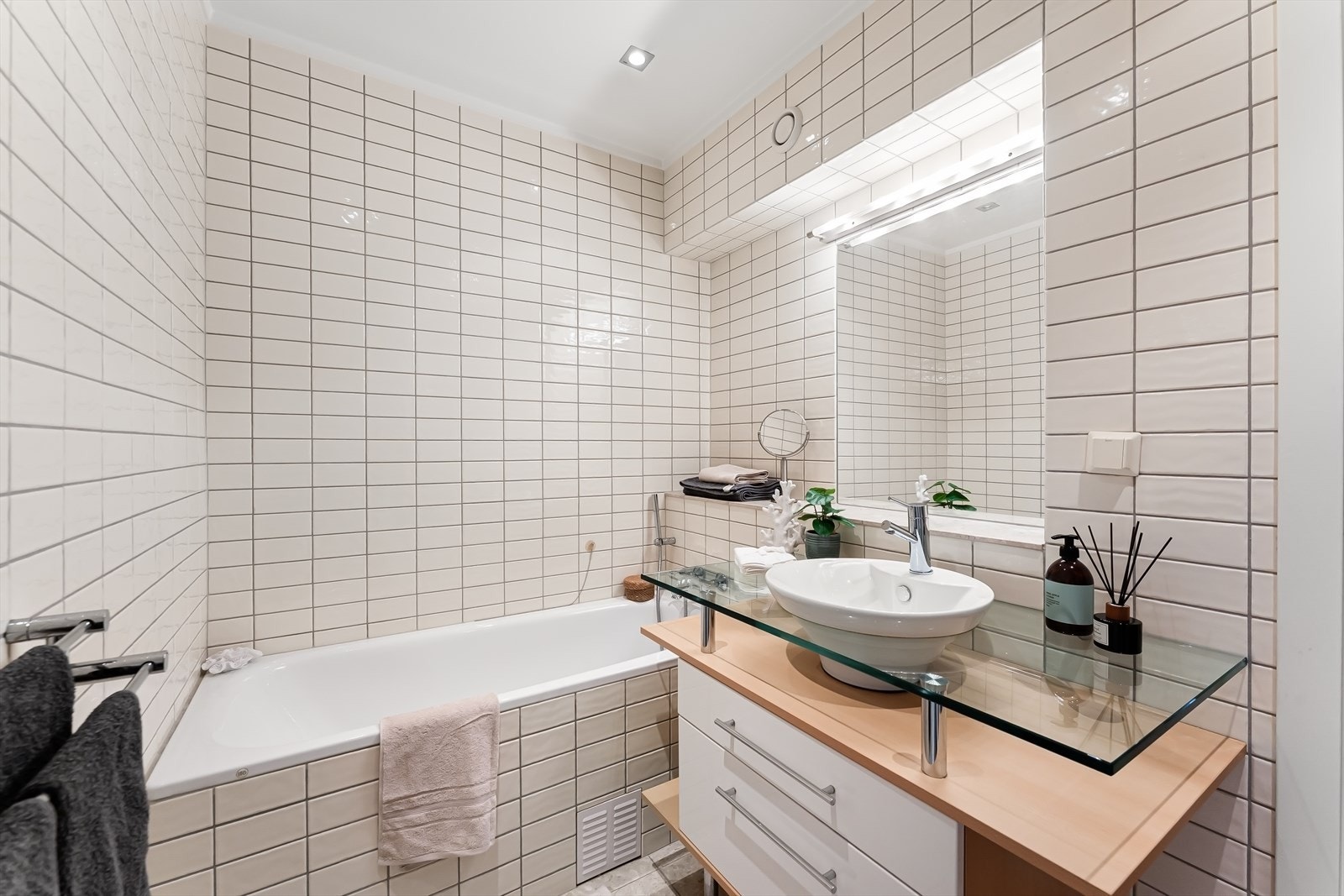 Baderommet pusset opp i 2005 med innmurt flislagt badekar, glass benkeplate med servant, underskap og speil i flis og lys over servant. Galleribilde