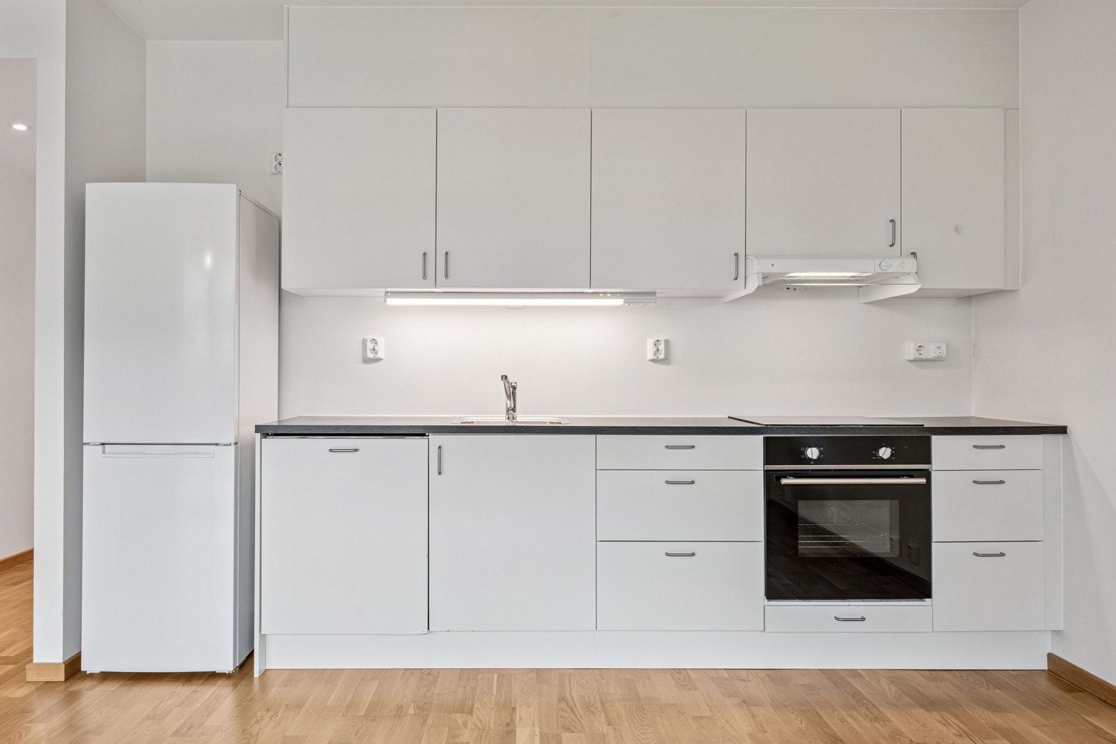 Kjøkkenet er lyst og moderne, med god oppbevaringsplass. Hvitevarene er integrerte og består av platetopp, stekeovn, oppvaskmaskin og kjøleskap med tilhørende frys. Galleribilde