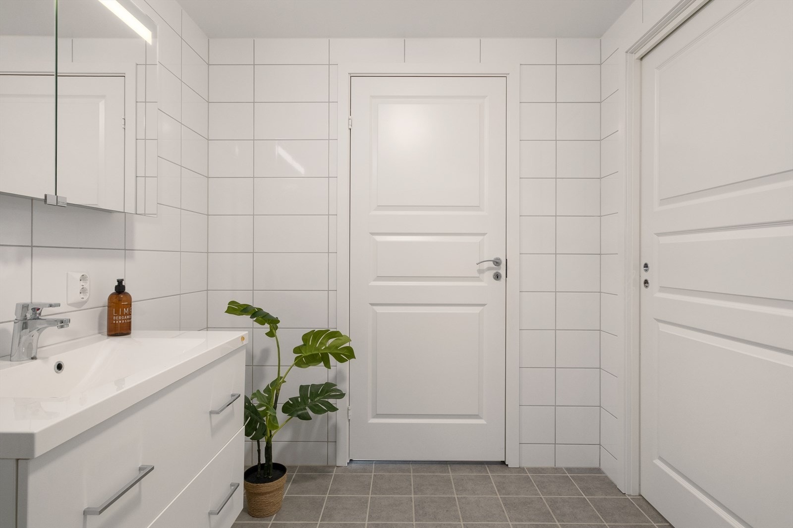 Leiligheten har et stort og pent helfliset bad med en moderne og tidløs utførelse. Det er skyvedør fra badet og inn til hovedsoverommet. Galleribilde
