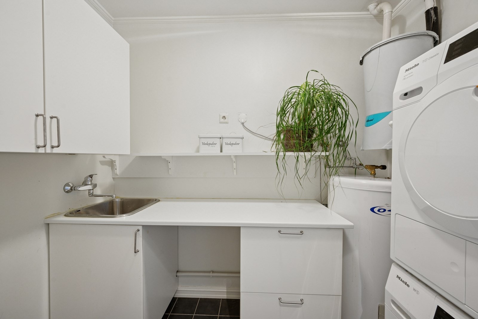 Vaskerom med nedfelt servant og opplegg for vaskemaskin. Det er balansert ventilasjon. Rommet har elektriske varmekabler. Galleribilde