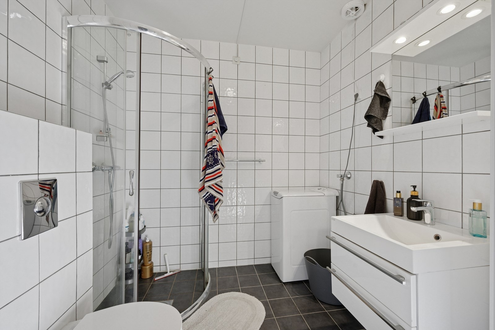 Flislagt baderom hybel - innredning med servant, veggmontert toalett og dusjvegger/hjørne. Galleribilde