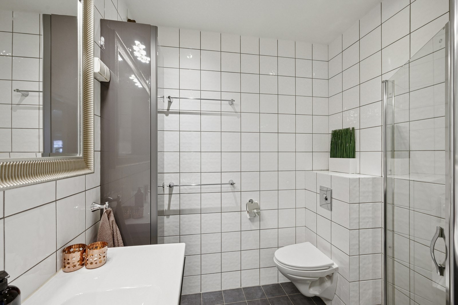 Pent, flislagt baderom i underetg./hoveddel har innredning med nedfelt servant, veggmontert toalett, dusjvegger/hjørne. Galleribilde
