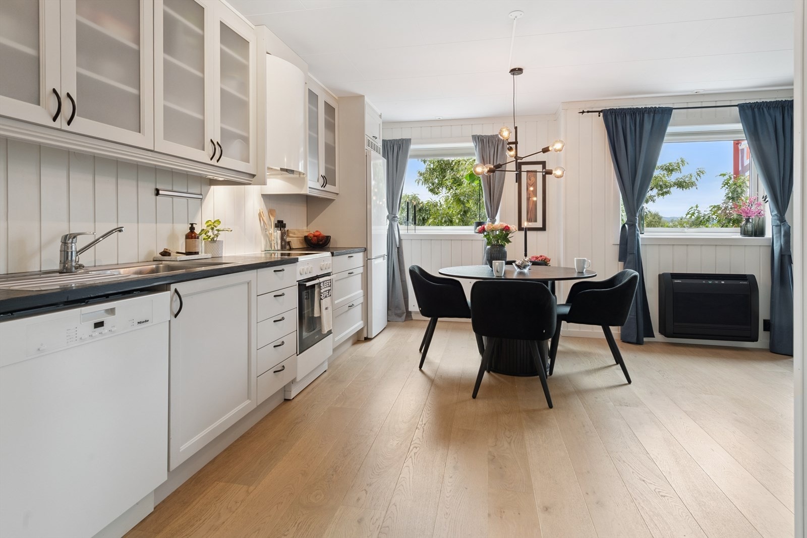 Pen takhøy kjøkkeninnredning med lakkerte fronter, laminat benkeplate, komfyrvakt og water guard. Galleribilde