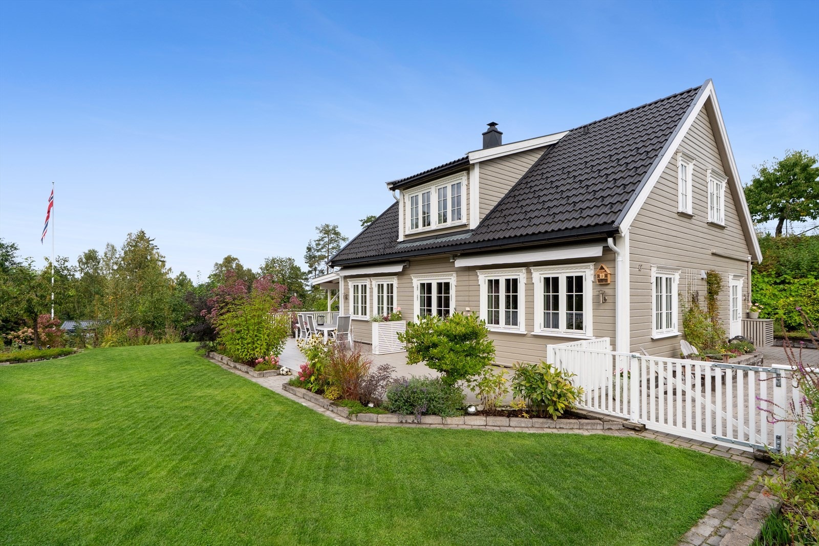 Tomten er meget pent opparbeidet med plenarealer, inngjerdet hage, diverse beplantninger som blomstrer året rundt og trær. Galleribilde