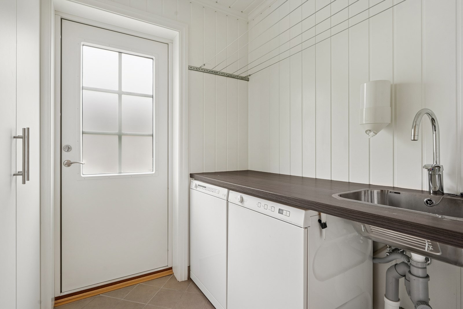 Vaskerommet er utstyrt med laminat benkeplate og utslagsvask, garderobeskap, samt opplegg for vaskemaskin. Herfra er det praktisk utgang. Galleribilde
