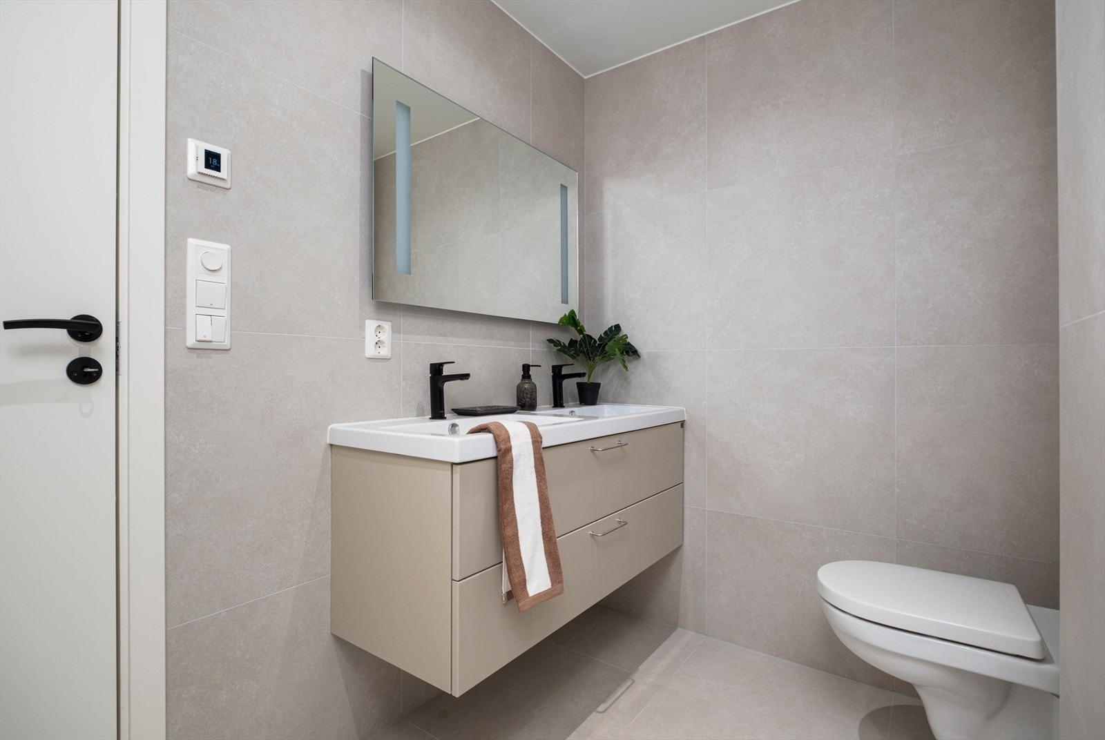 Innredningen er med vegghengt toalett, dimmbare spotter i tak, speil med integrert belysning, gulvvarme, dusjhjørne med glassdører og opplegg for vaskemaskin. Galleribilde