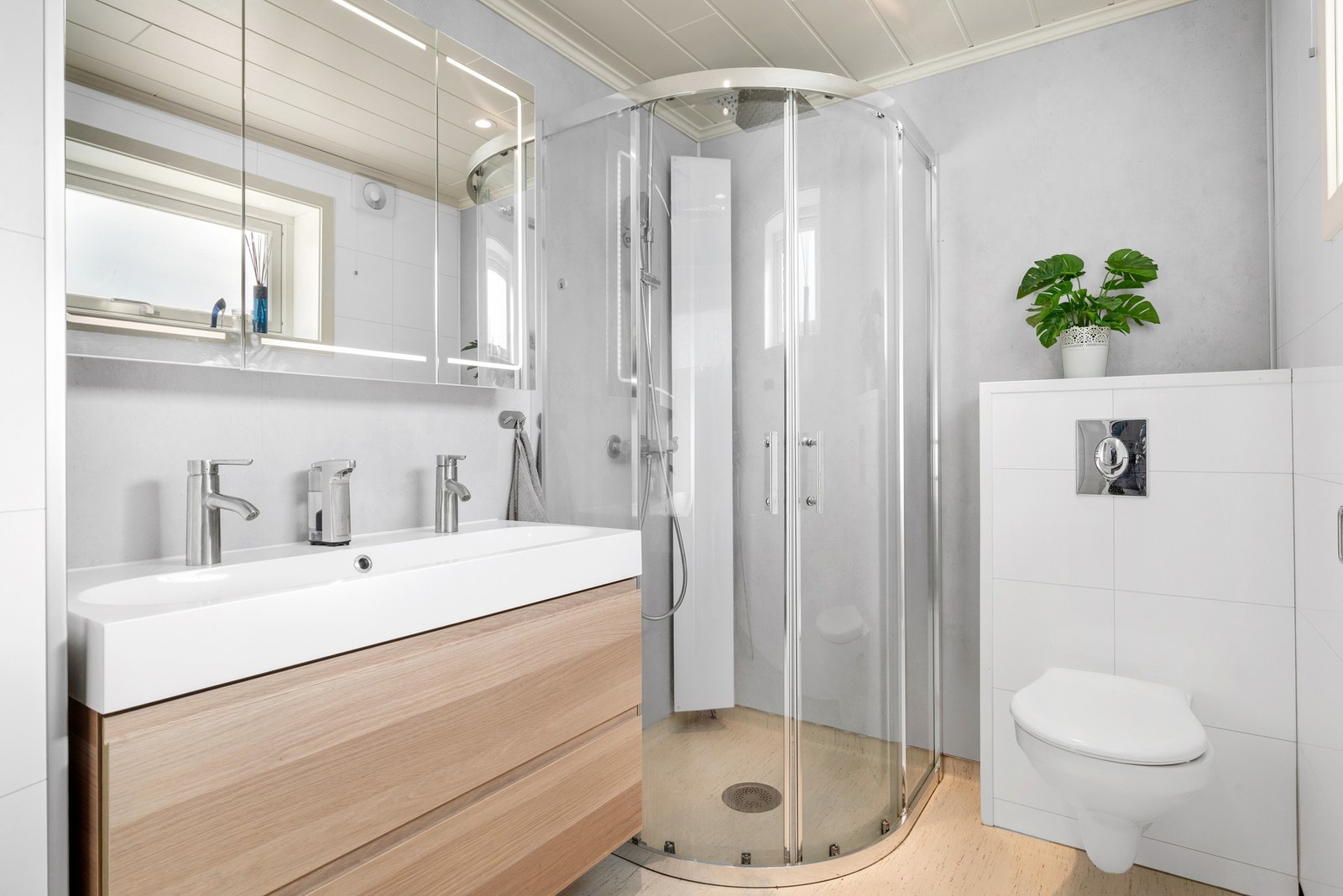 Innredet med åpen dusjløsning, vegghengt servant toalett og opplegg for vaskemaskin. Galleribilde