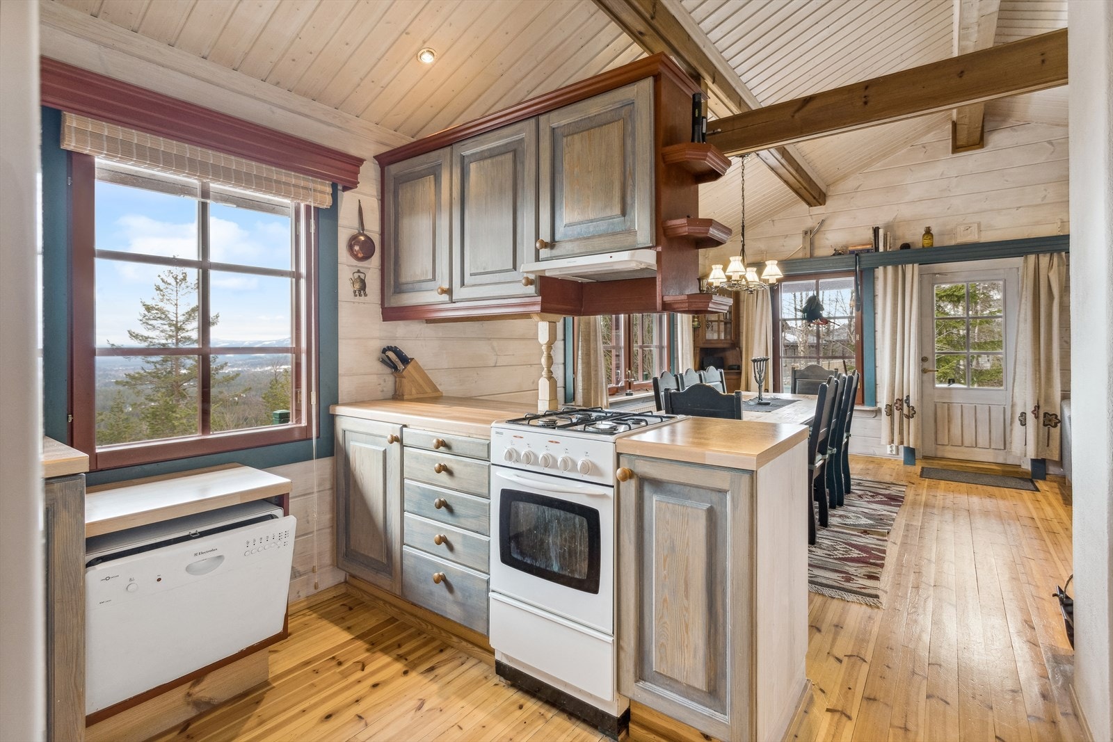 Kjøkken med enkel innredning og åpen løsning for komfyr. Galleribilde