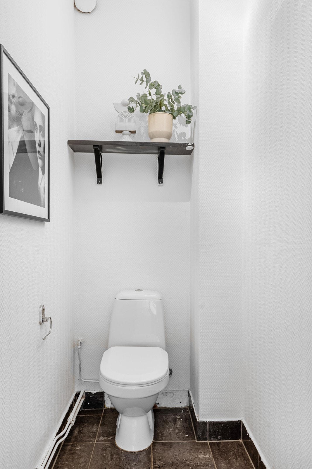 Vegg-i-vegg med badet ligger et praktisk toalettrom med flislagt gulv, hvitmalte overflater og toalett. Galleribilde