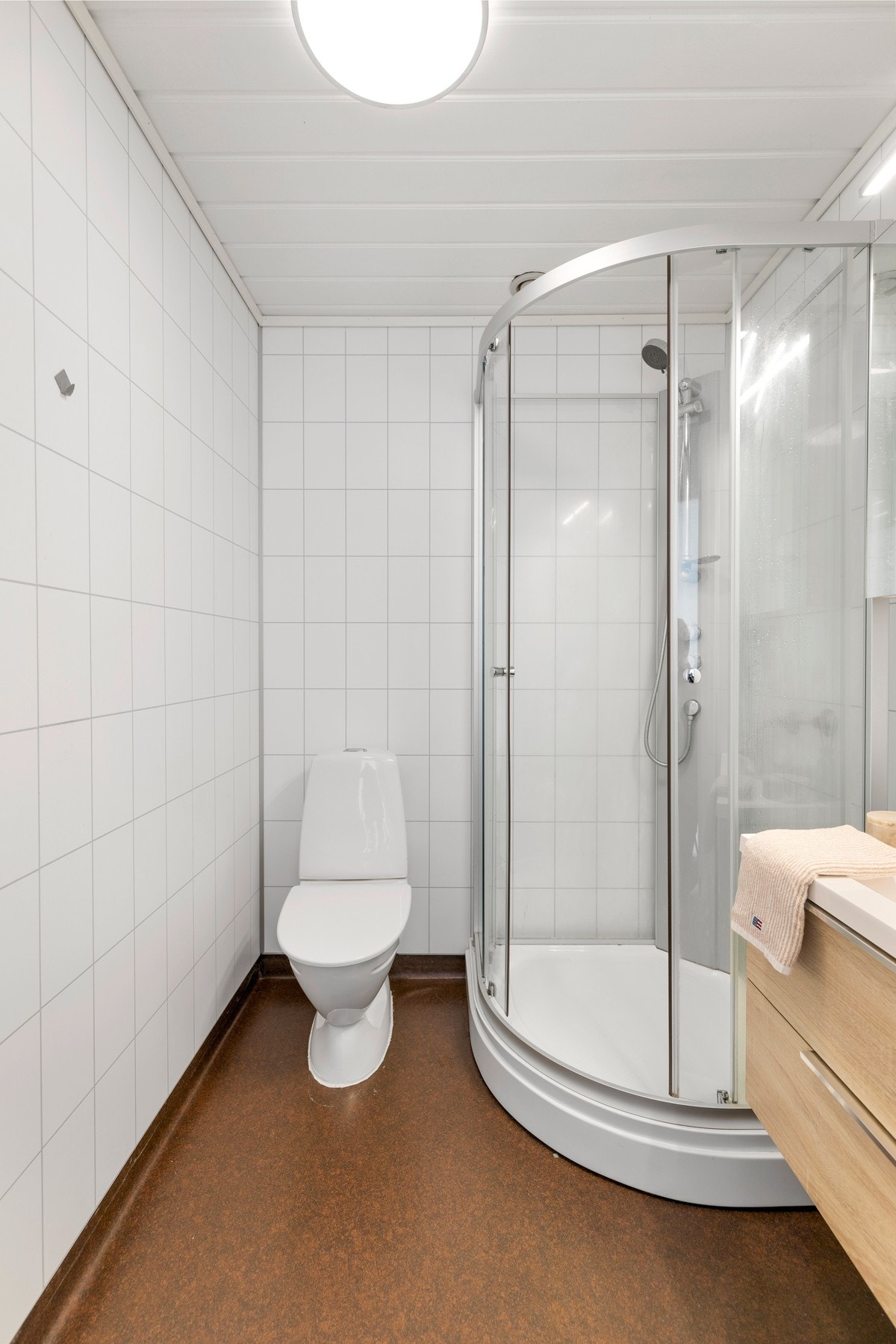 Badet har belegg på gulv og våtromsplater på vegger. Rommet er videre utstyrt med toalett, dusjkabinett og baderomsinnredning med servant. Galleribilde