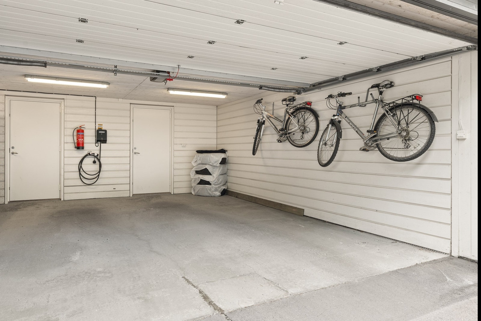 I nabohuset bak har boligen 2 garasjeplasser med elbillader og praktisk sportsbod i bakkant av den ene plassen Galleribilde