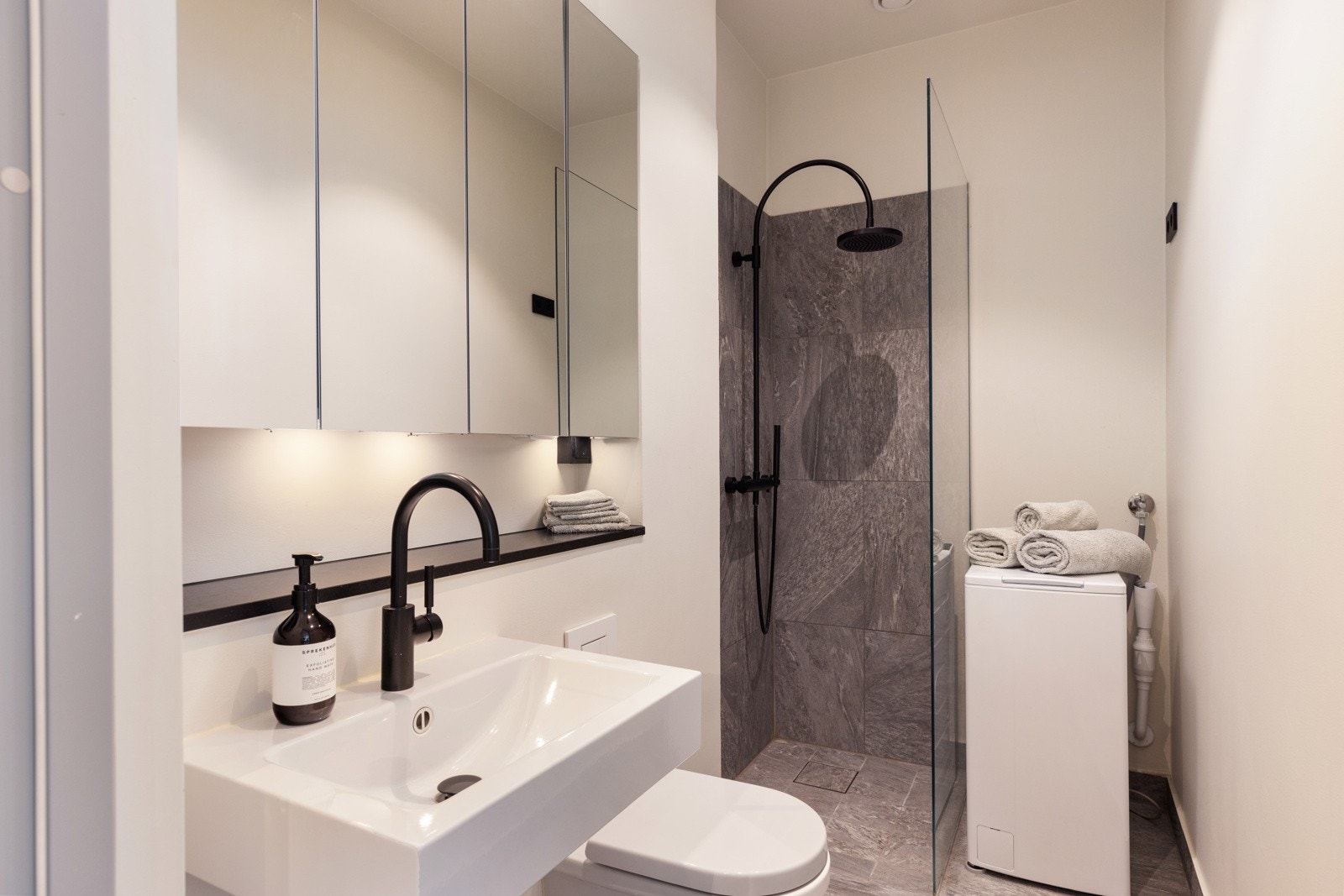 Flott flislagt bad med lekkert speilskap, glassdusjvegg og veggmontert klosett. Galleribilde