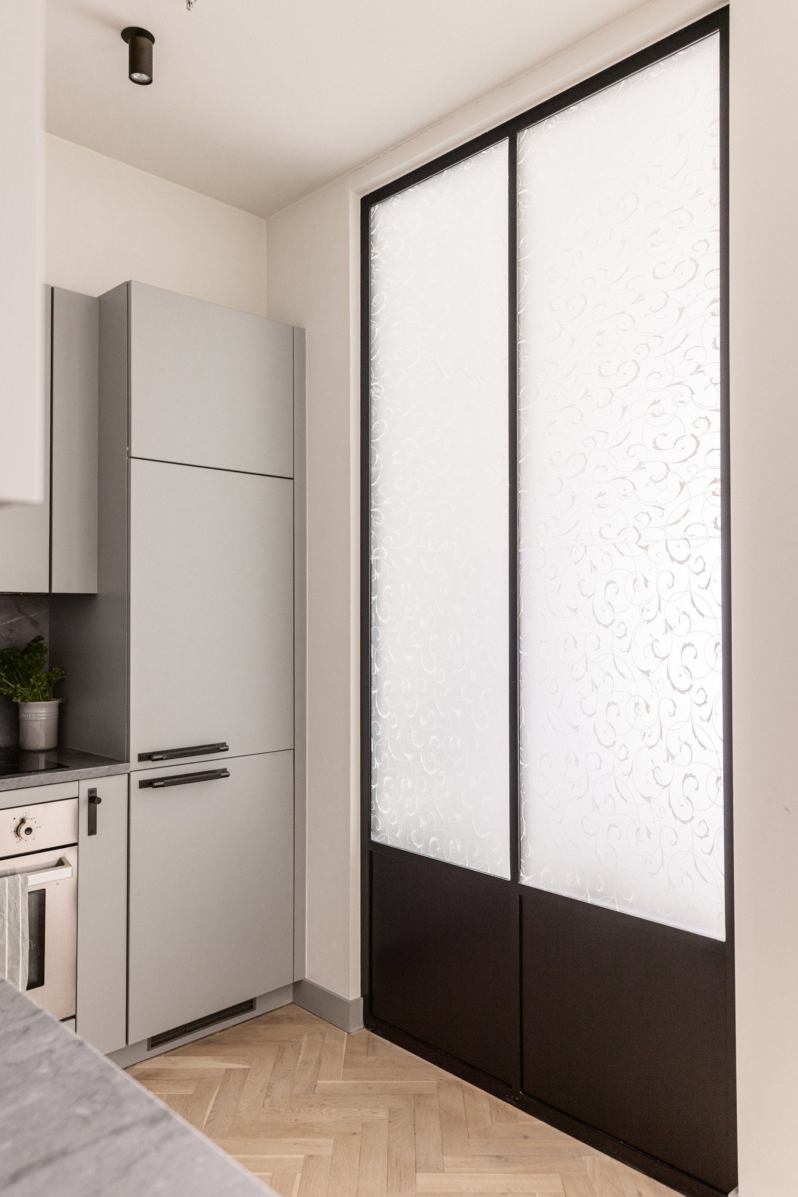 Delvis glass-/smijernsvegg mellom kjøkken og soverom slik at lyset fra vinduet faller inn i kjøkkenet. Galleribilde