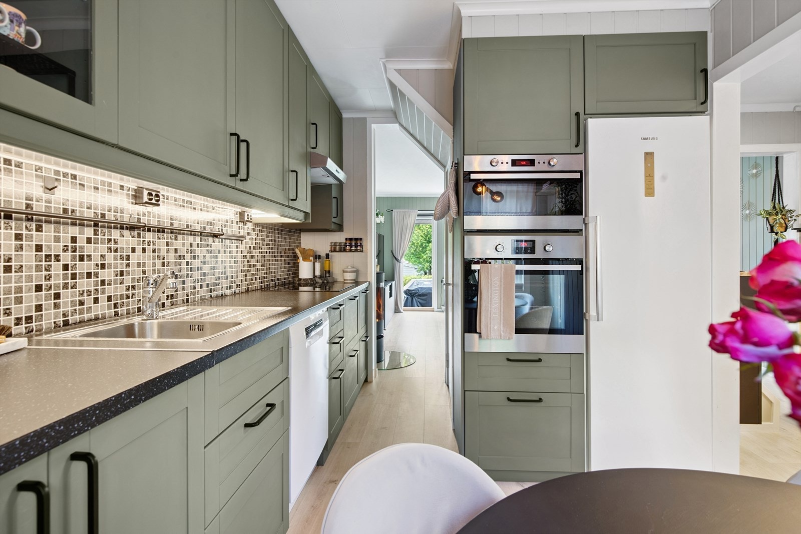 Kjøkkeninnredningen har malte (2023) profilerte fronter, vinylbelegg over kjøkkenbenk, samt innebygget platetopp, stekeovn og mikrobølgeovn. Galleribilde